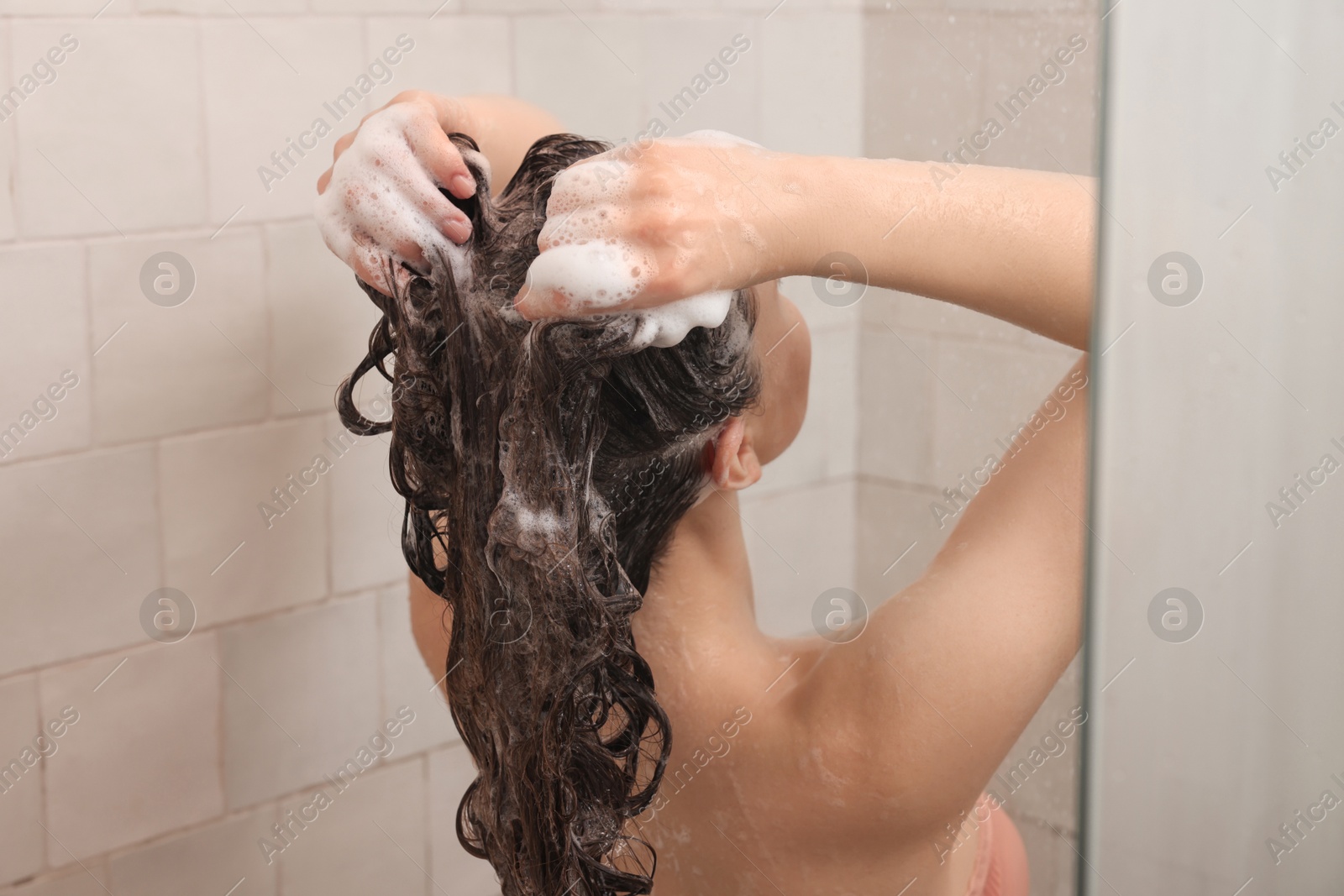 Photo of Young woman washing hair while taking shower at home