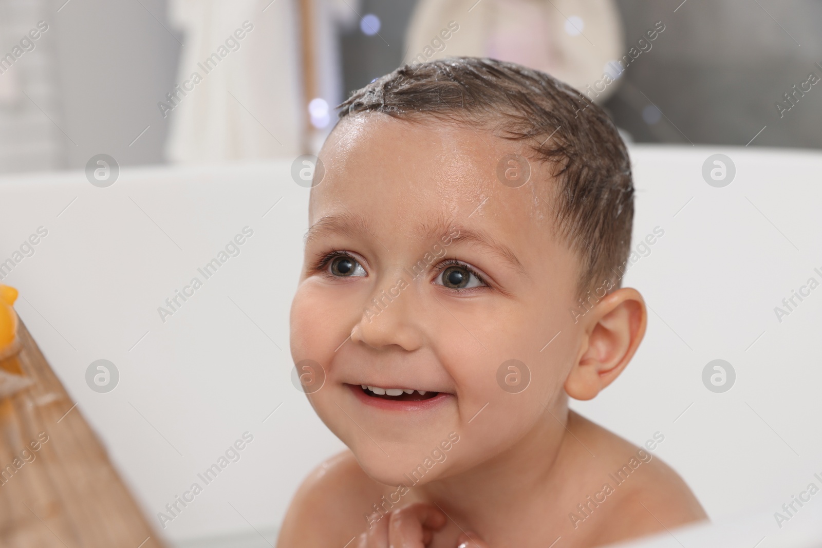 Photo of Cute little boy washing hair with shampoo in bathroom, closeup