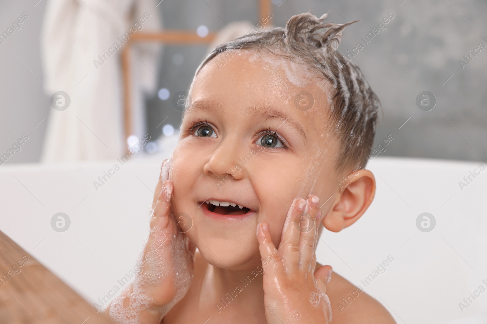 Photo of Cute little boy washing hair with shampoo in bathroom, closeup