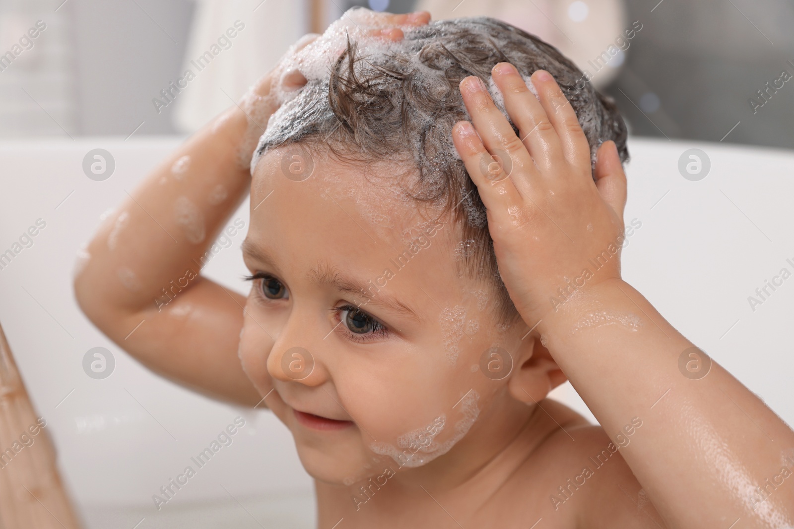 Photo of Cute little boy washing hair with shampoo in bathroom, closeup