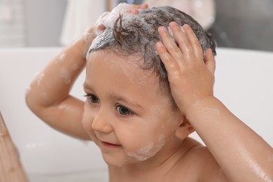 Photo of Cute little boy washing hair with shampoo in bathroom, closeup