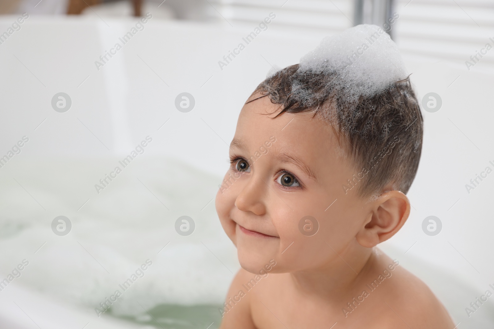 Photo of Cute little boy washing hair with shampoo in bathroom. Space for text