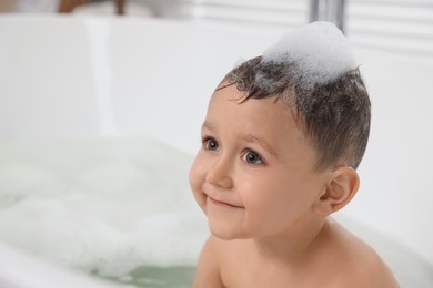 Cute little boy washing hair with shampoo in bathroom. Space for text