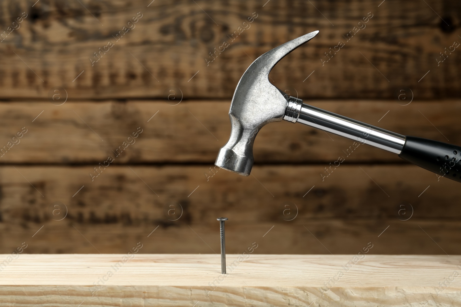 Photo of Hammering nail into plank against wooden background, space for text