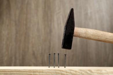 Photo of Hammering nail into plank against wooden background, space for text