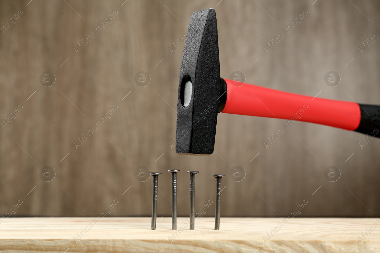 Photo of Hammering nail into plank against wooden background