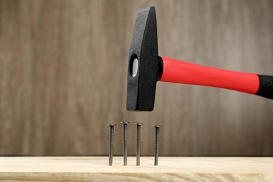 Photo of Hammering nail into plank against wooden background