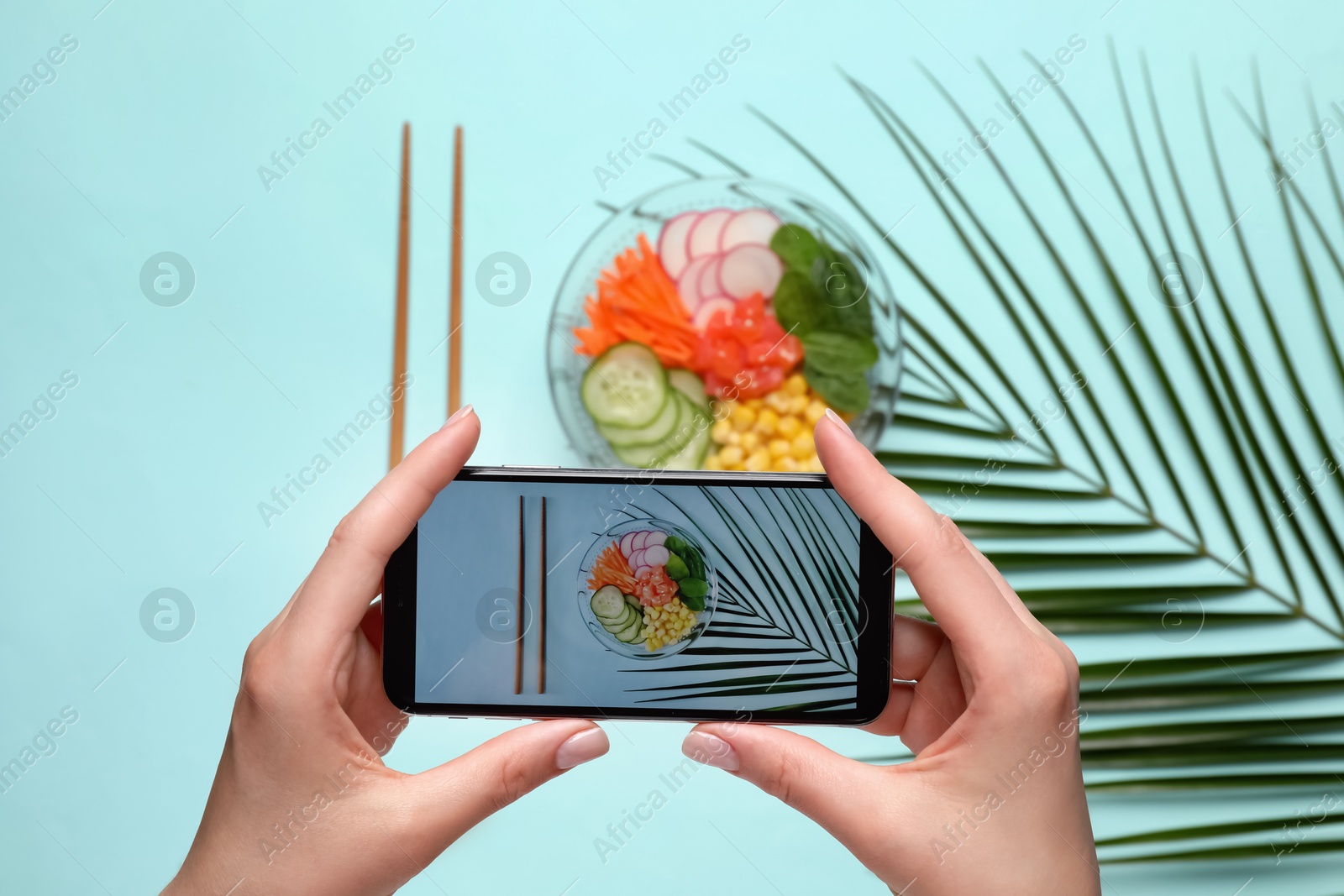 Photo of Blogger taking photo of lunch on turquoise background, top view