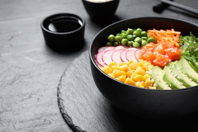 Photo of Delicious salad with salmon, vegetables and seaweed on black table, closeup. Space for text