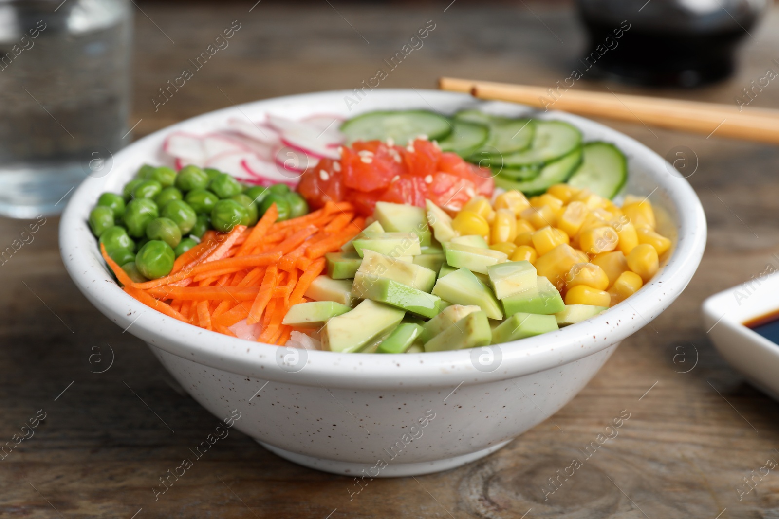 Photo of Delicious salad with salmon and vegetables on wooden table, closeup