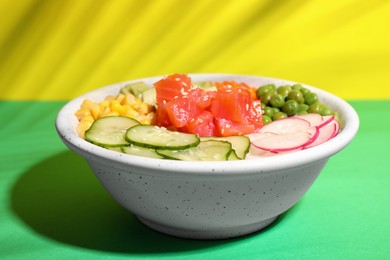 Photo of Delicious salad with salmon and vegetables in bowl on color background
