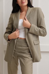 Photo of Woman in formal suit near light grey wall, closeup. Business attire