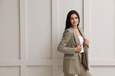 Photo of Beautiful woman in formal suit near light grey wall. Business attire