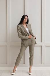 Photo of Full length portrait of beautiful woman in formal suit near light grey wall. Business attire