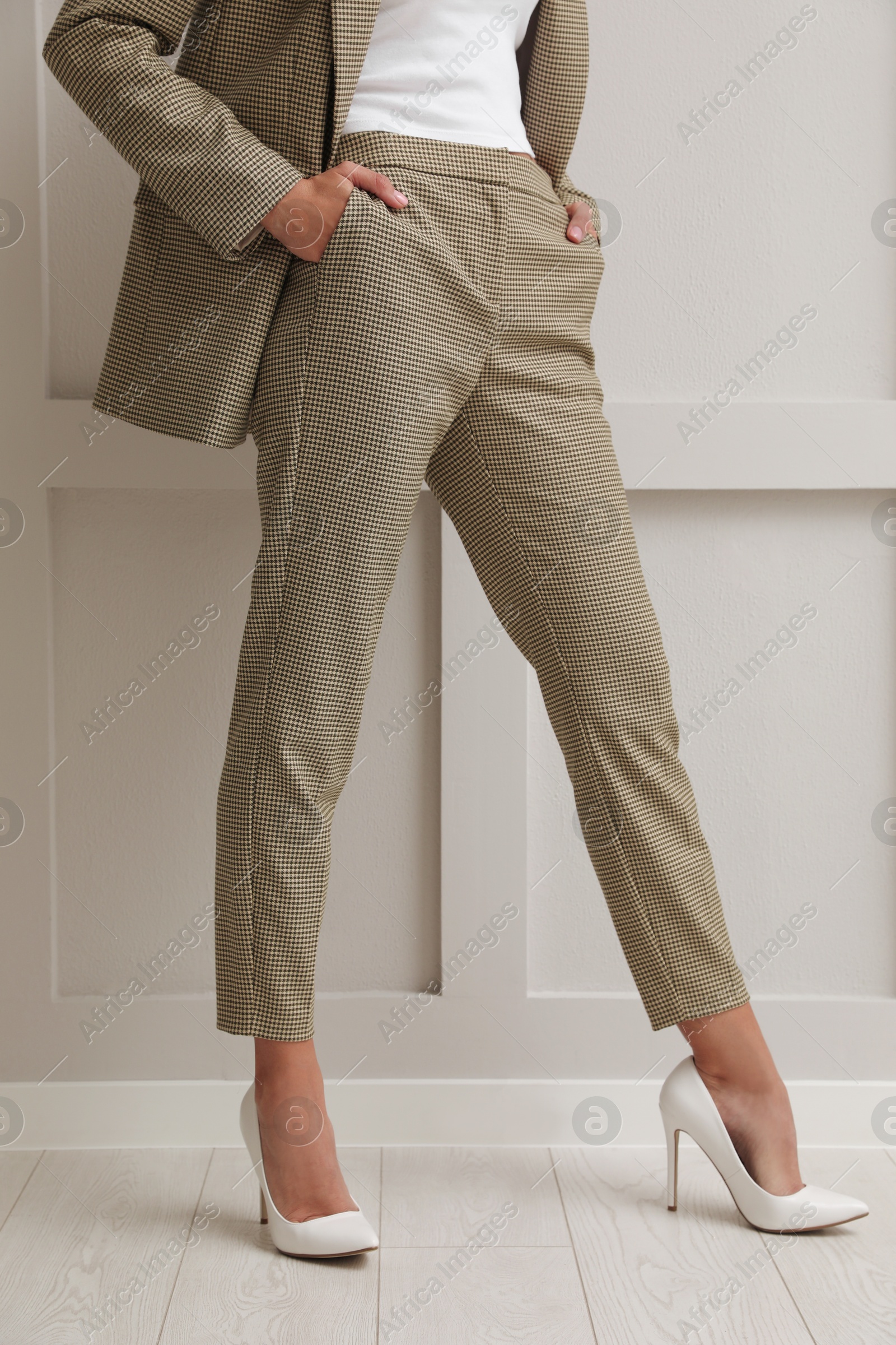 Photo of Woman in formal suit near light grey wall, closeup. Business attire