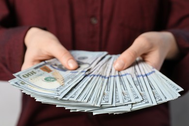 Woman counting dollar banknotes on light background, closeup