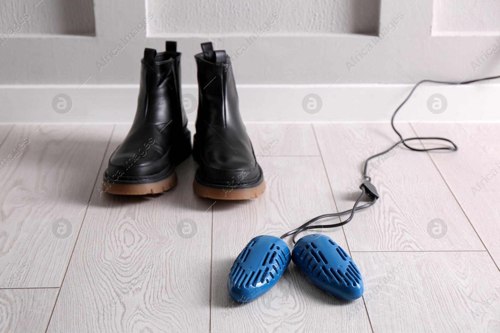 Photo of Shoes and electric dryer on floor indoors