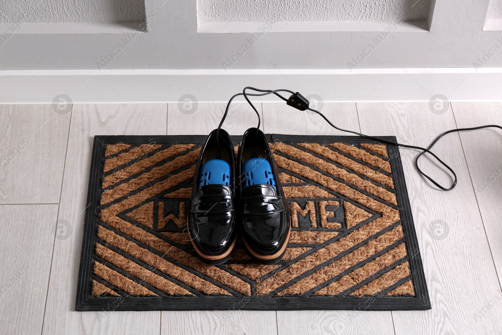 Photo of Shoes with electric dryer on rug indoors