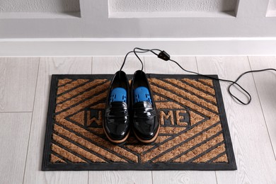 Shoes with electric dryer on rug indoors