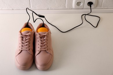 Photo of Shoes with electric dryer on floor indoors, space for text