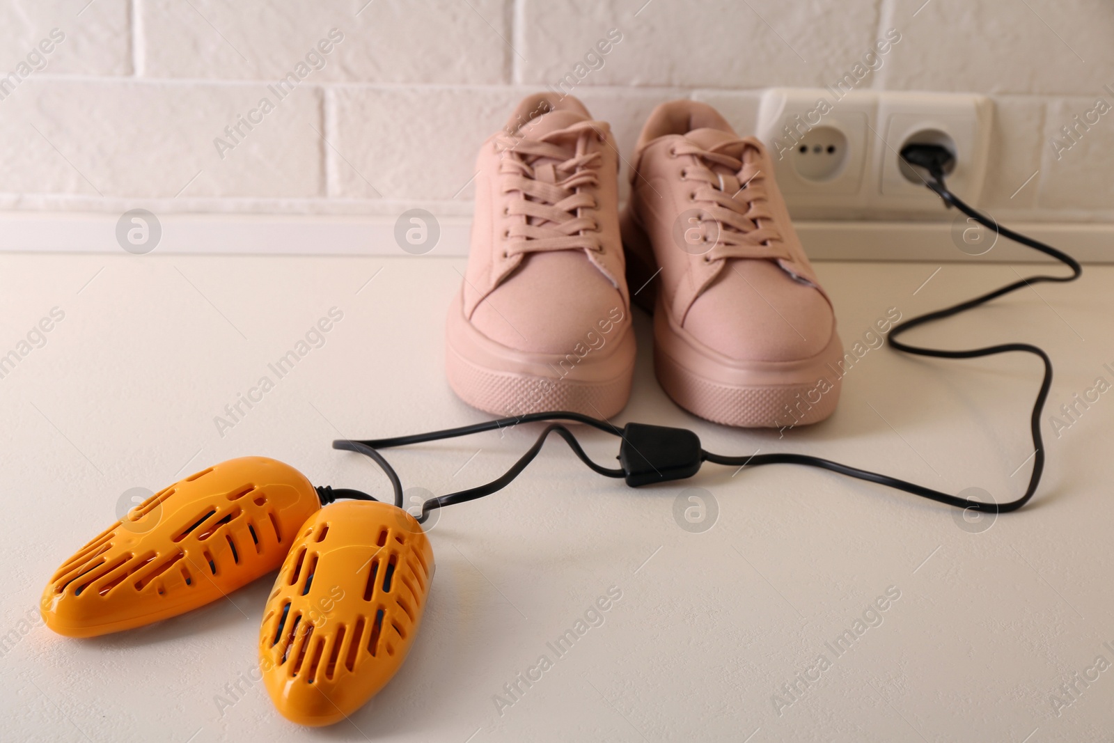 Photo of Shoes and electric dryer on floor indoors