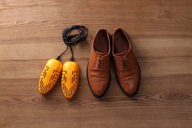 Shoes and electric dryer on wooden background, flat lay