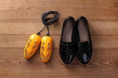 Photo of Shoes and electric dryer on wooden background, flat lay