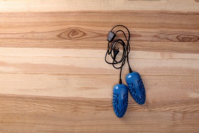 Electric shoe dryer on wooden background, top view. Space for text