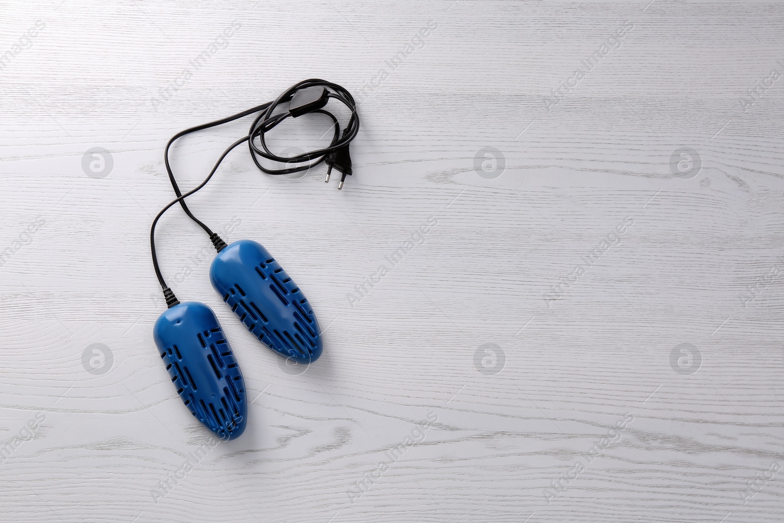 Photo of Electric shoe dryer on white wooden background, top view. Space for text