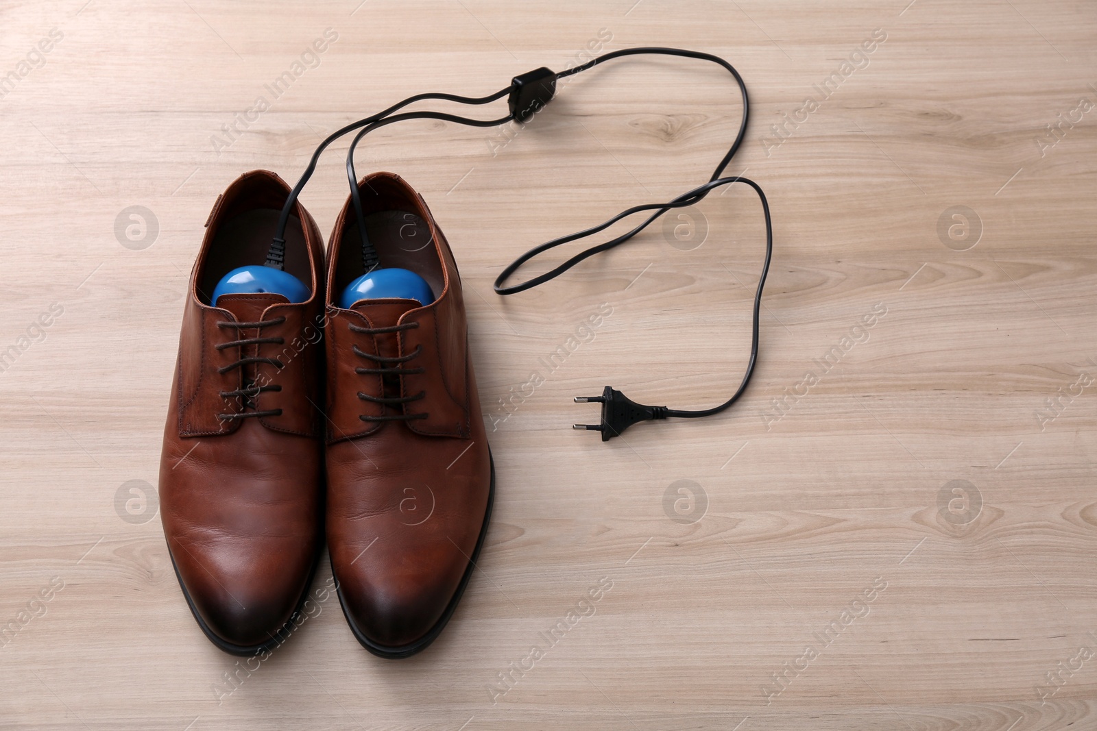 Photo of Shoes with electric dryer on wooden background, space for text