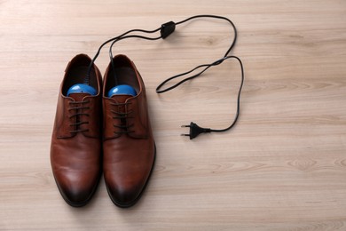 Photo of Shoes with electric dryer on wooden background, space for text