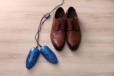 Photo of Shoes and electric dryer on wooden background, above view