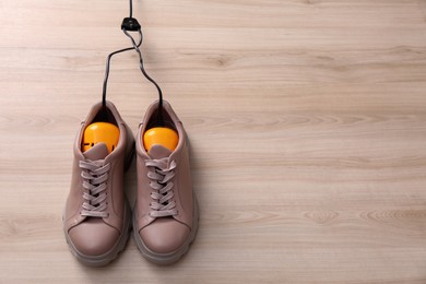 Photo of Shoes with electric dryer on wooden background, space for text