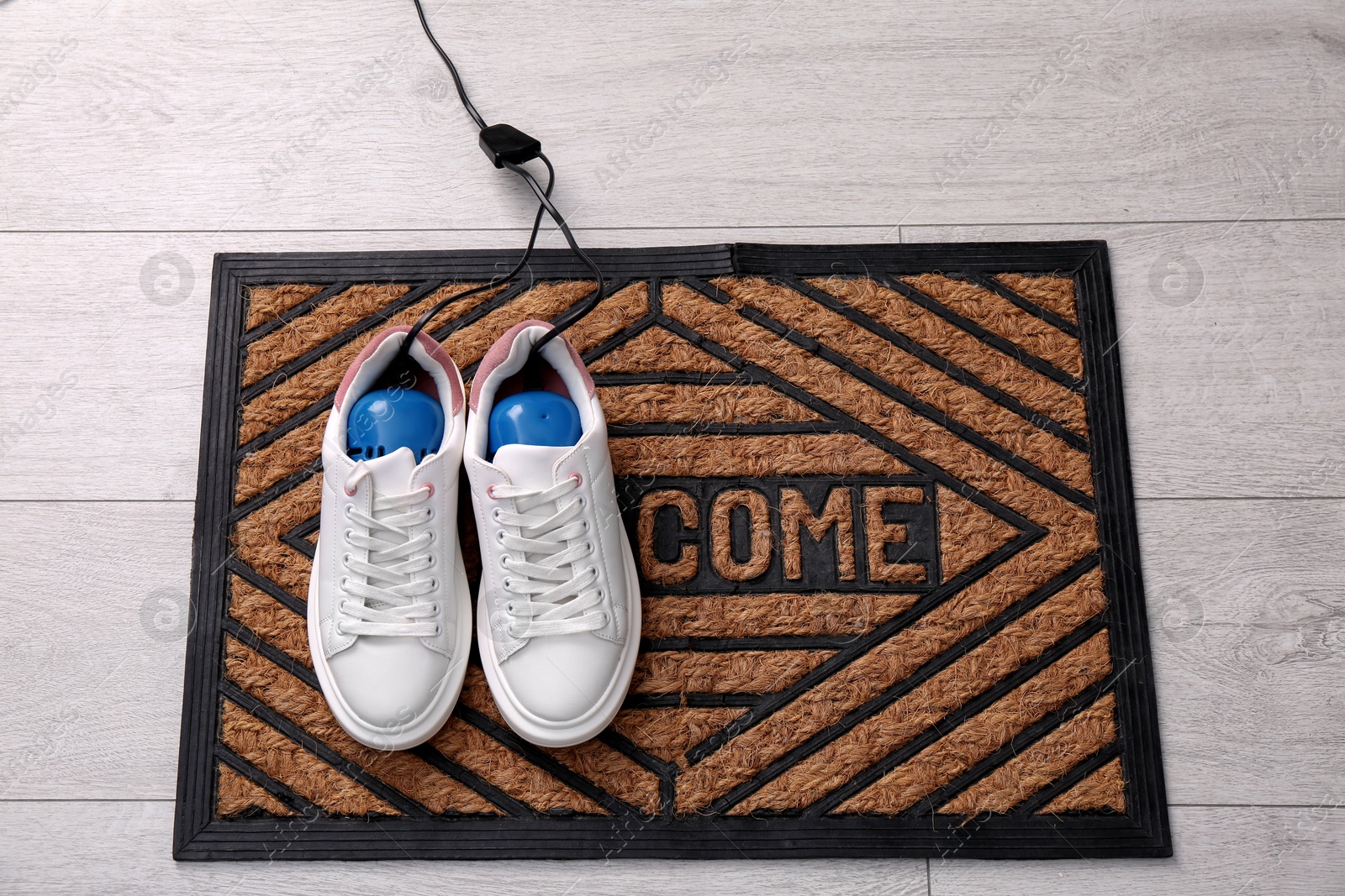 Photo of Shoes with electric dryer on rug indoors, above view