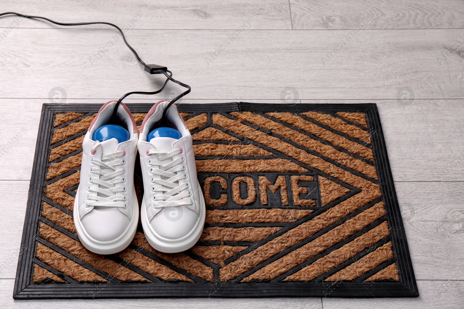 Photo of Shoes with electric dryer on rug indoors