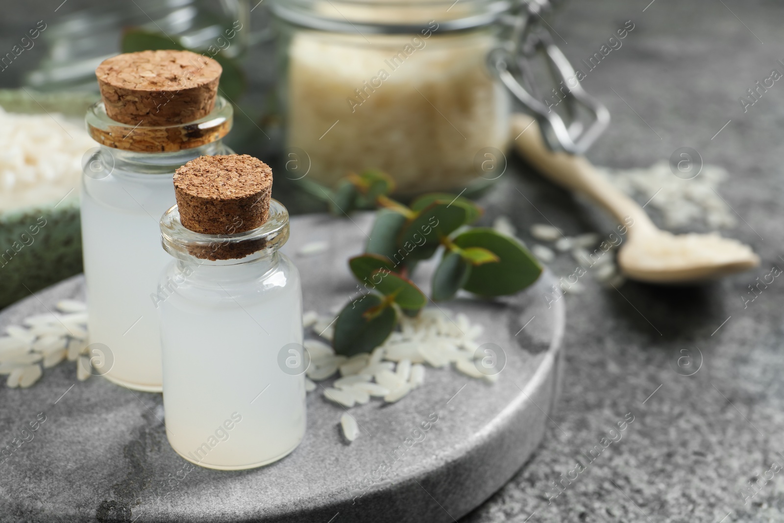 Photo of Glass bottles with rice water on grey table. Space for text