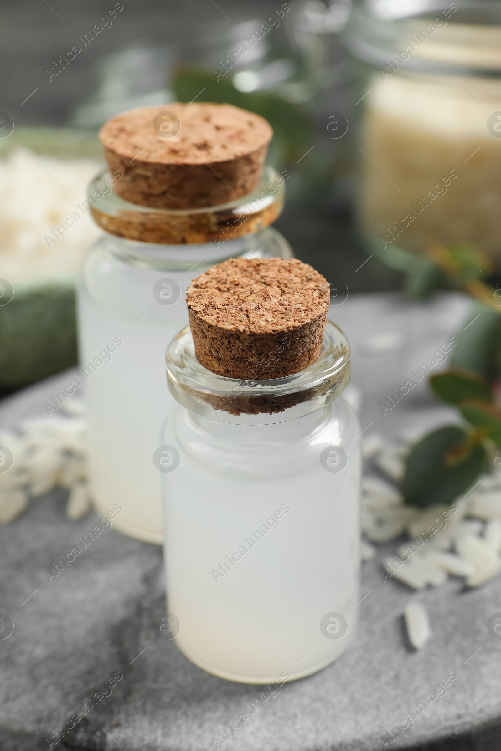 Photo of Glass bottles with rice water on grey marble table, closeup