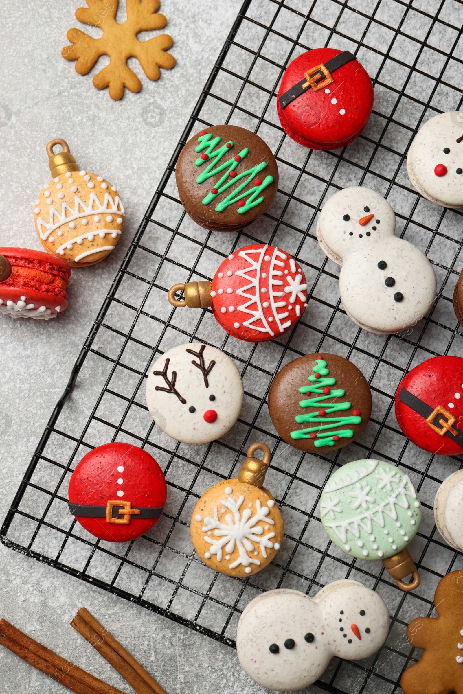 Photo of Beautifully decorated Christmas macarons and cinnamon on light grey table, flat lay