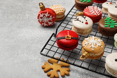Photo of Beautifully decorated Christmas macarons on light grey table, closeup. Space for text