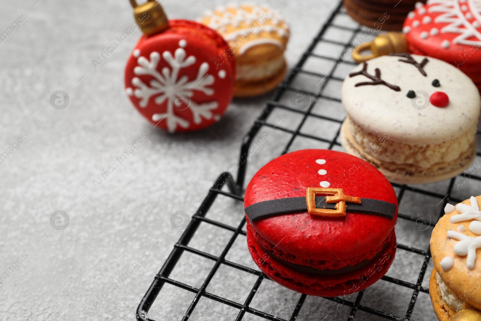 Photo of Beautifully decorated Christmas macarons on light grey table, closeup. Space for text