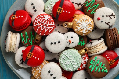Photo of Beautifully decorated Christmas macarons on light blue table, top view