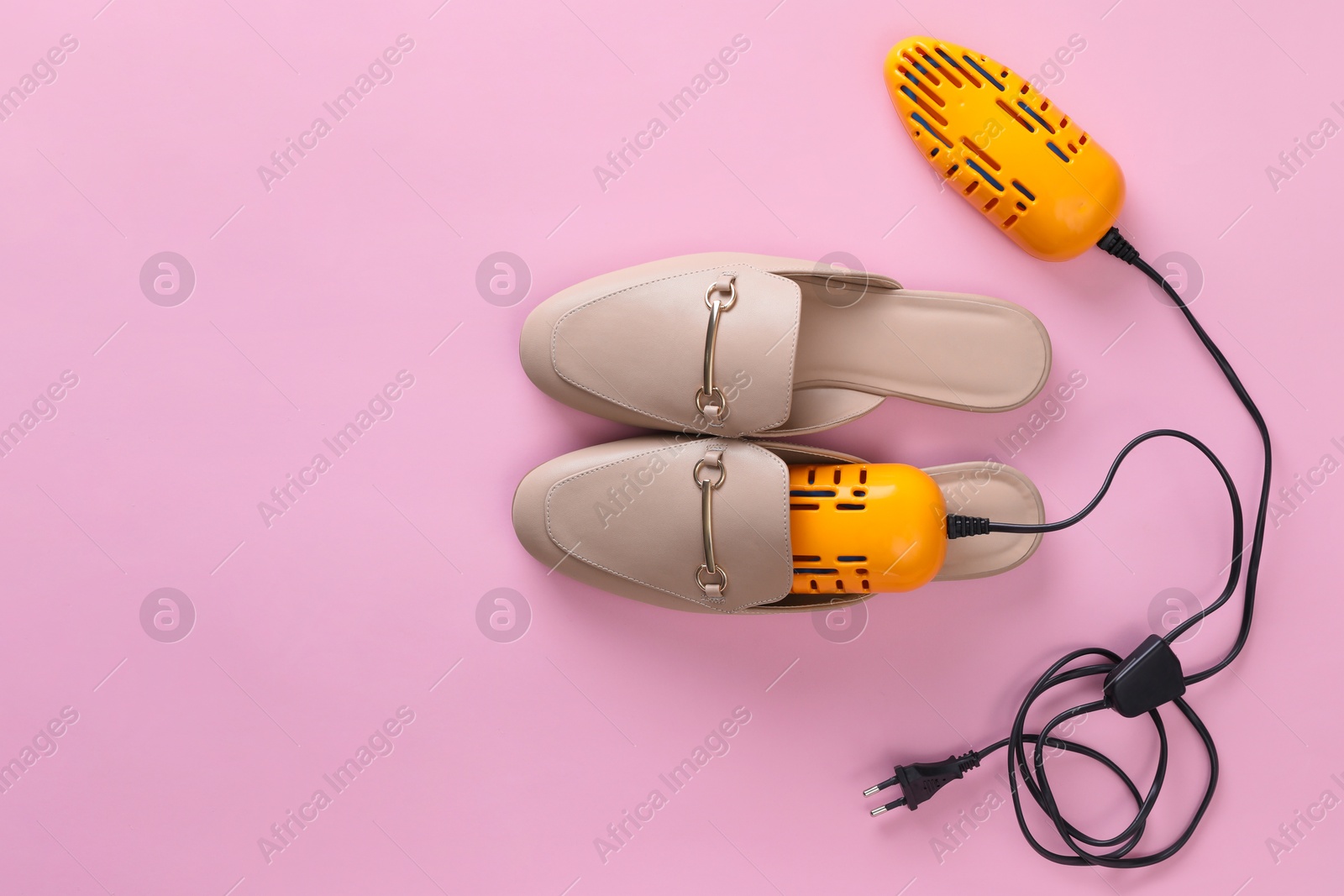 Photo of Pair of stylish shoes with modern electric footwear dryer on pink background, top view. Space for text