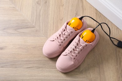 Pair of stylish shoes with modern electric footwear dryer on floor indoors. Space for text