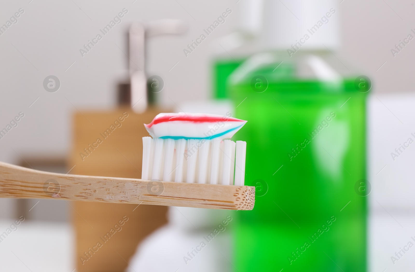 Photo of Toothbrush with paste near mouthwash on blurred background, closeup