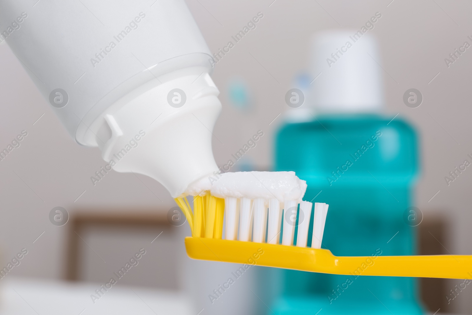 Photo of Applying paste on toothbrush near mouthwash, closeup