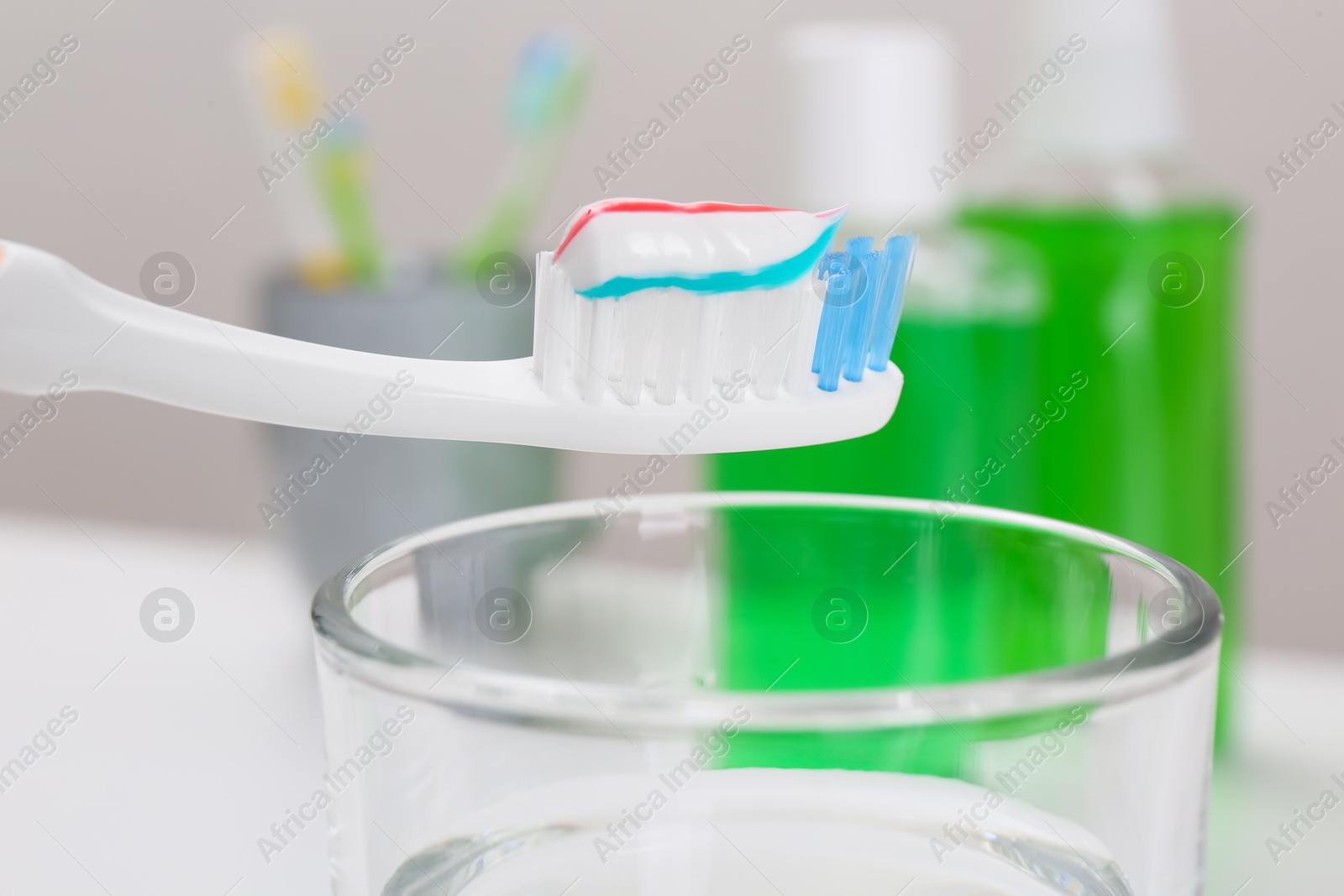 Photo of Toothbrush with paste near mouthwash on blurred background, closeup