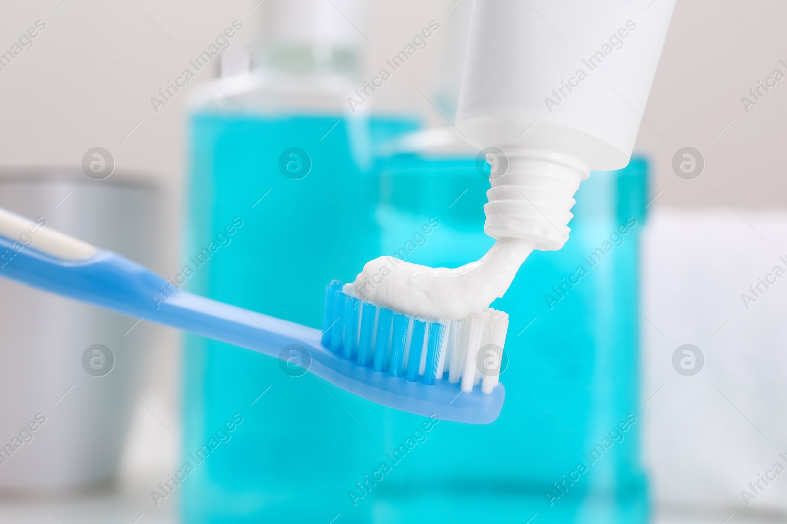 Photo of Applying paste on toothbrush near mouthwash, closeup