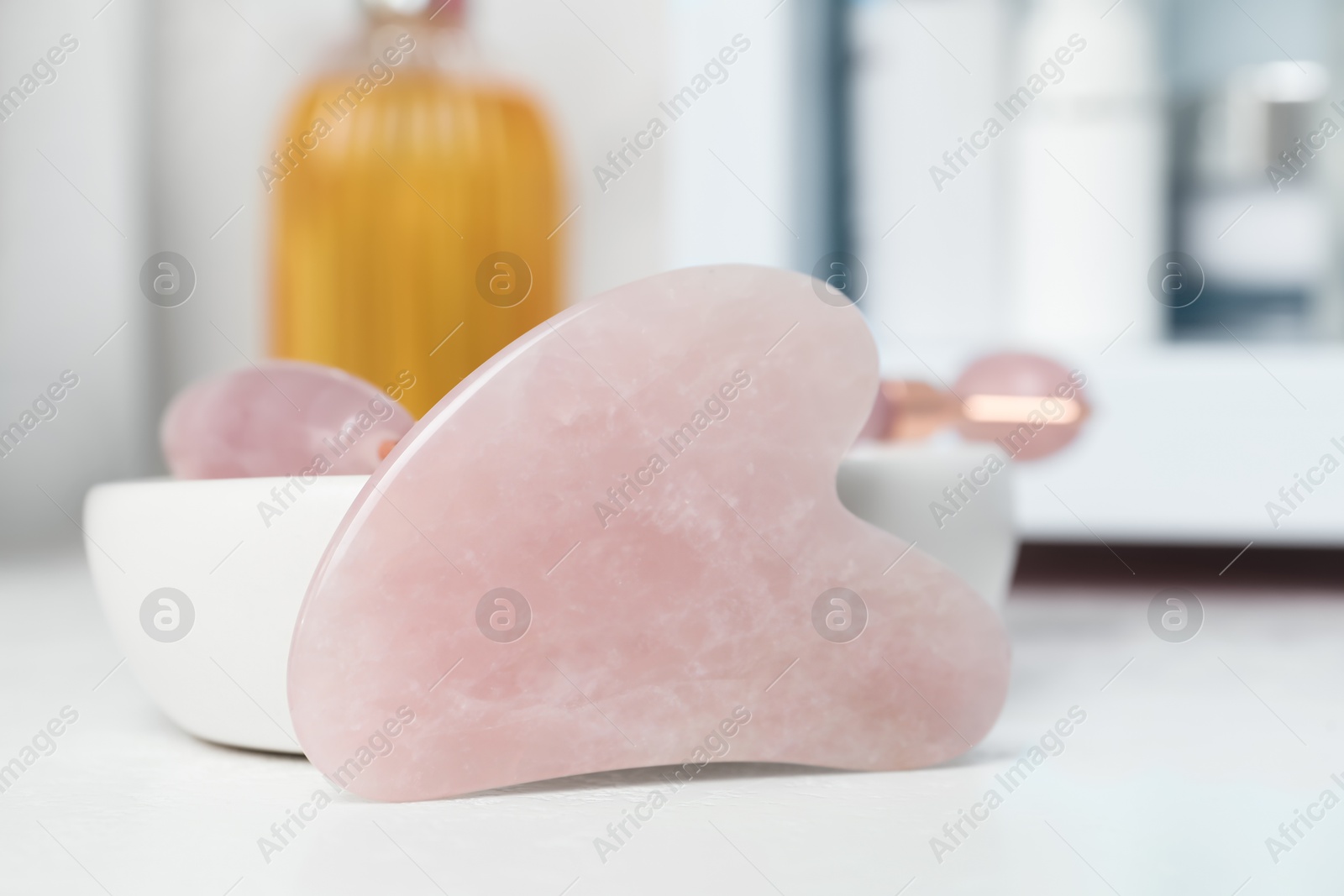 Photo of Rose quartz gua sha tool on white table, closeup