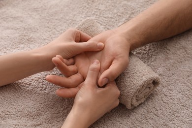 Photo of Man receiving hand massage on soft towel, closeup