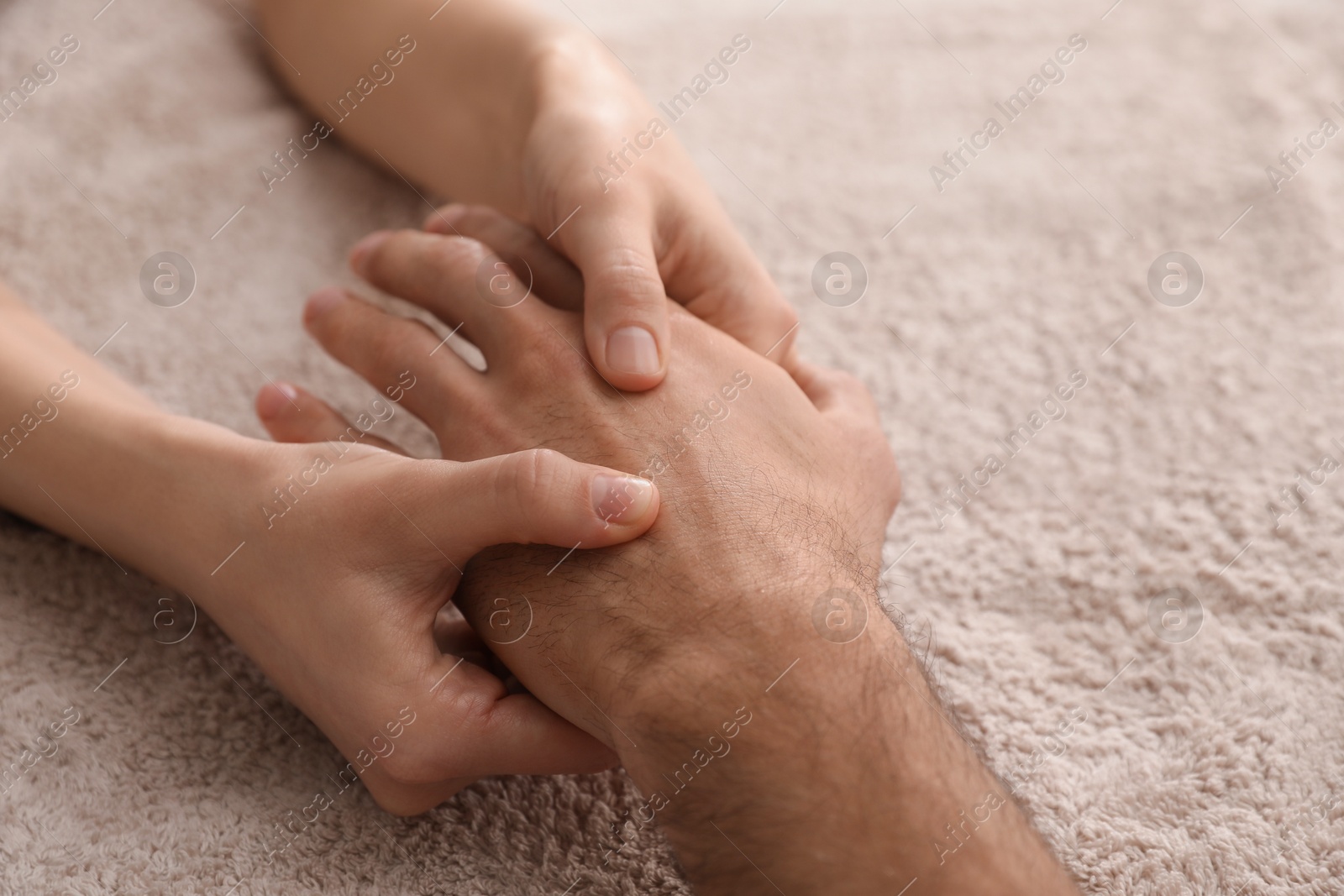 Photo of Man receiving hand massage on soft towel, closeup